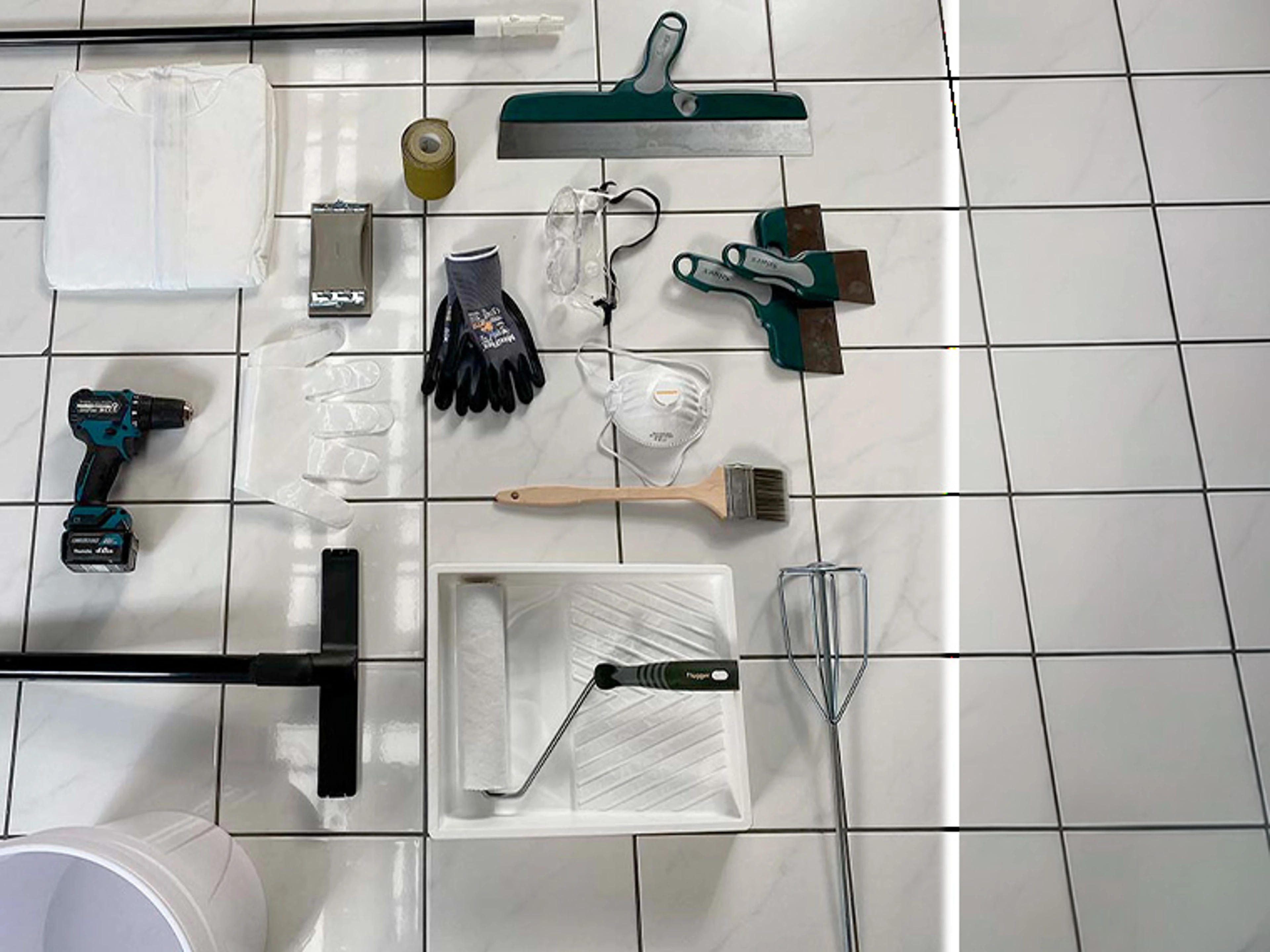 Flisleggingsverktøy og tilbehør lagt ut på et hvitt flisegulv. Bildet viser blant annet sparkler, fugebrett, rulle, pensel, rørepisk, malerbrett, verneutstyr, hansker og batteridrevet drill til forberedelse og behandling av gulvfliser.
