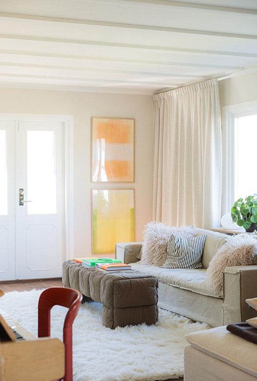Bright living room with white ceiling beams, a linen sofa and a white shag rug.