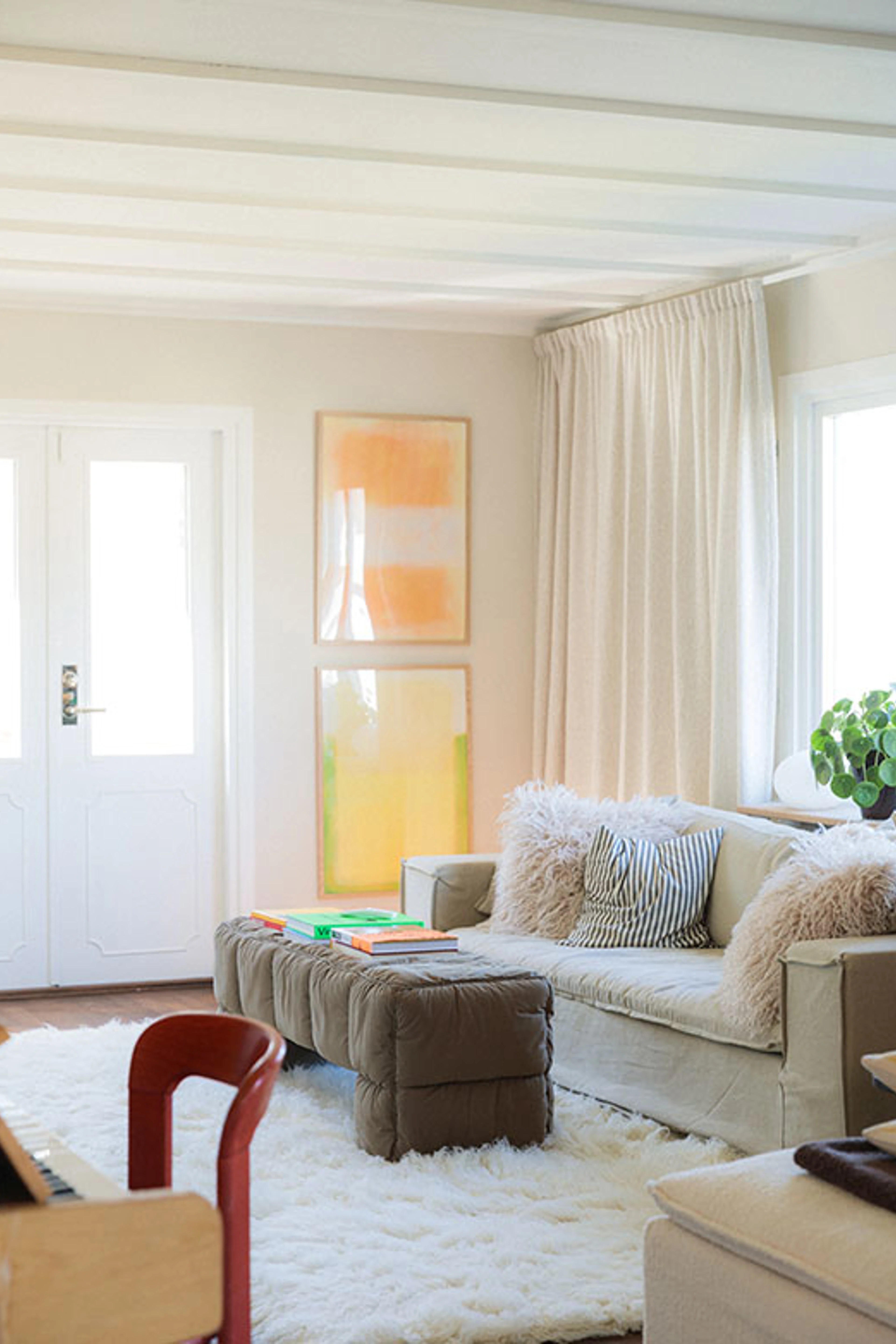 Bright living room with white ceiling beams, a linen sofa and a white shag rug.