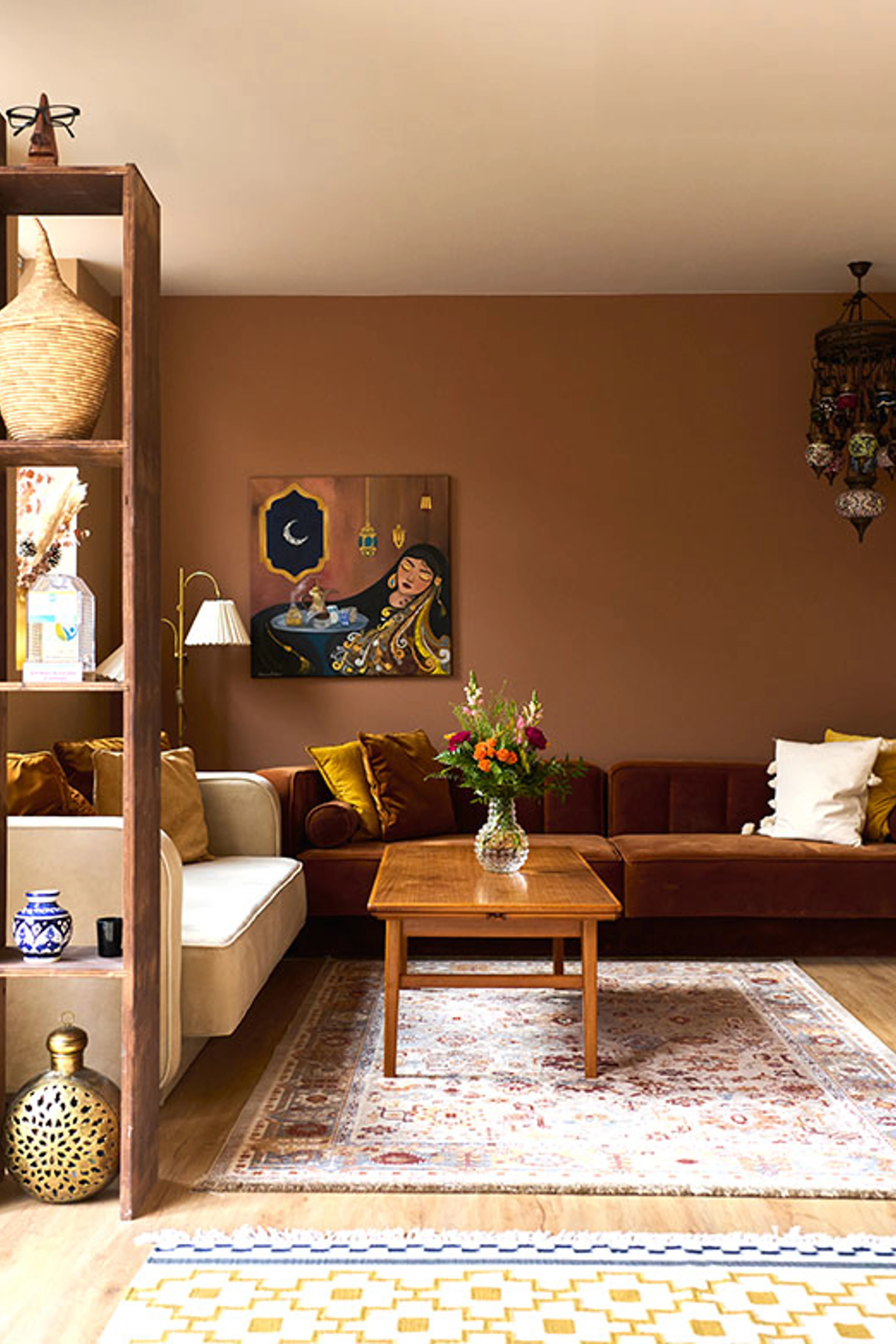 Warm living room with a brown wall, sofa, Oriental rug, wooden table, colorful cushions, and decorative art objects.
