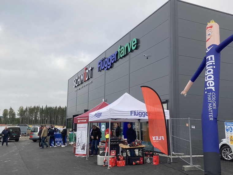 Flügger-butik med stor facade og Flügger farve-skiltning. Foran indgangen er der opstillet telte og produktudstillinger ved et kundeevent.