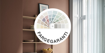Farvegaranti-logo placeret foran et interiør med brun væg, åben reol og vindue. Logoet viser en vifte af farveprøver i forskellige nuancer.