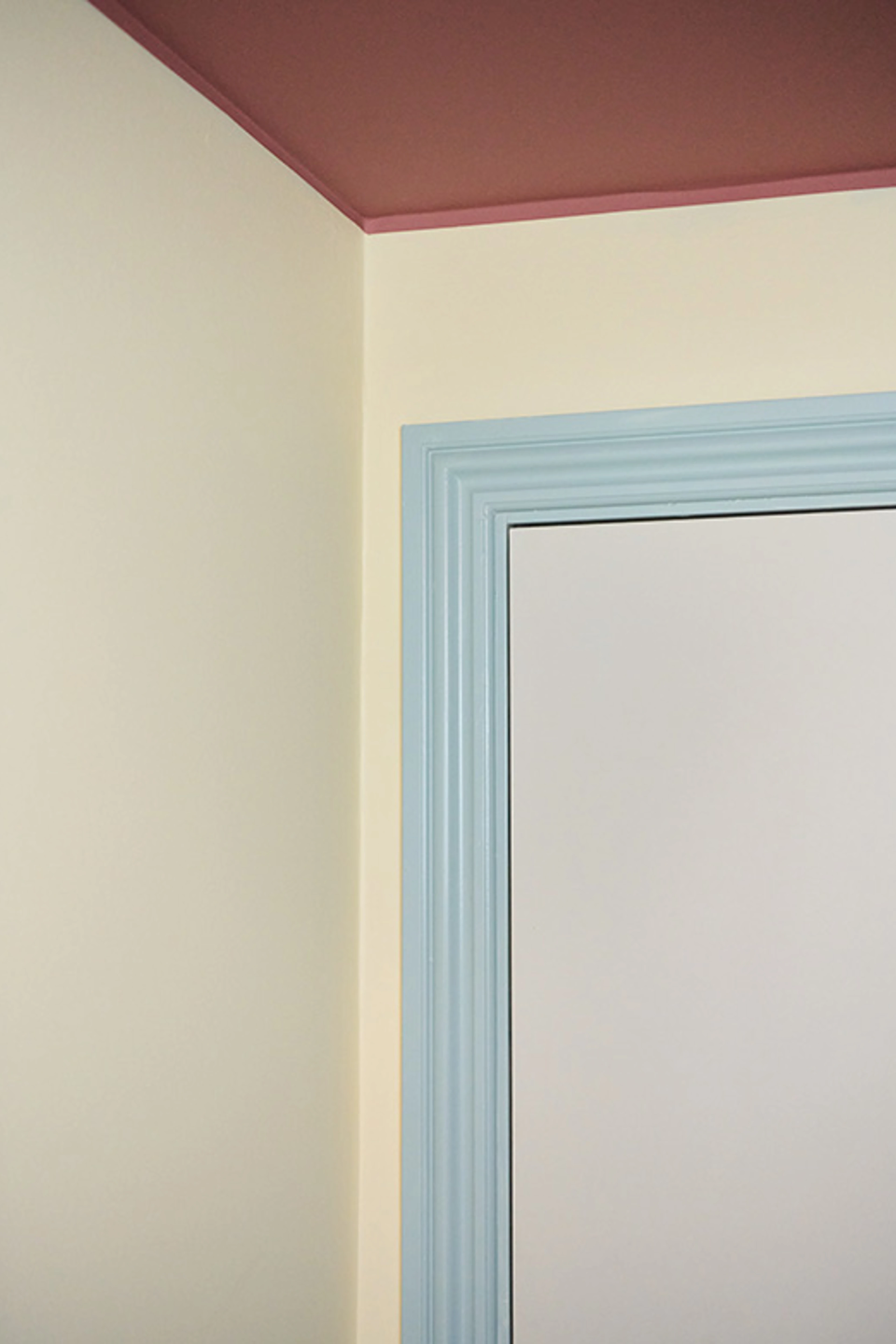 Detalje af rum med lyse vægge, rosa loft og dørkarm i lys blå nuance.