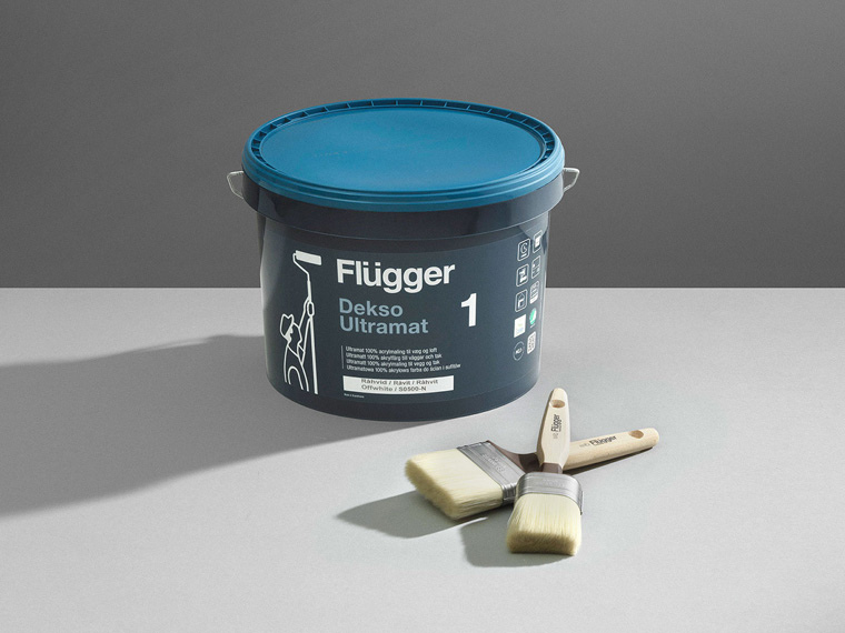 Image of Dekso 1 from Flügger and paint brushes on a grey table.