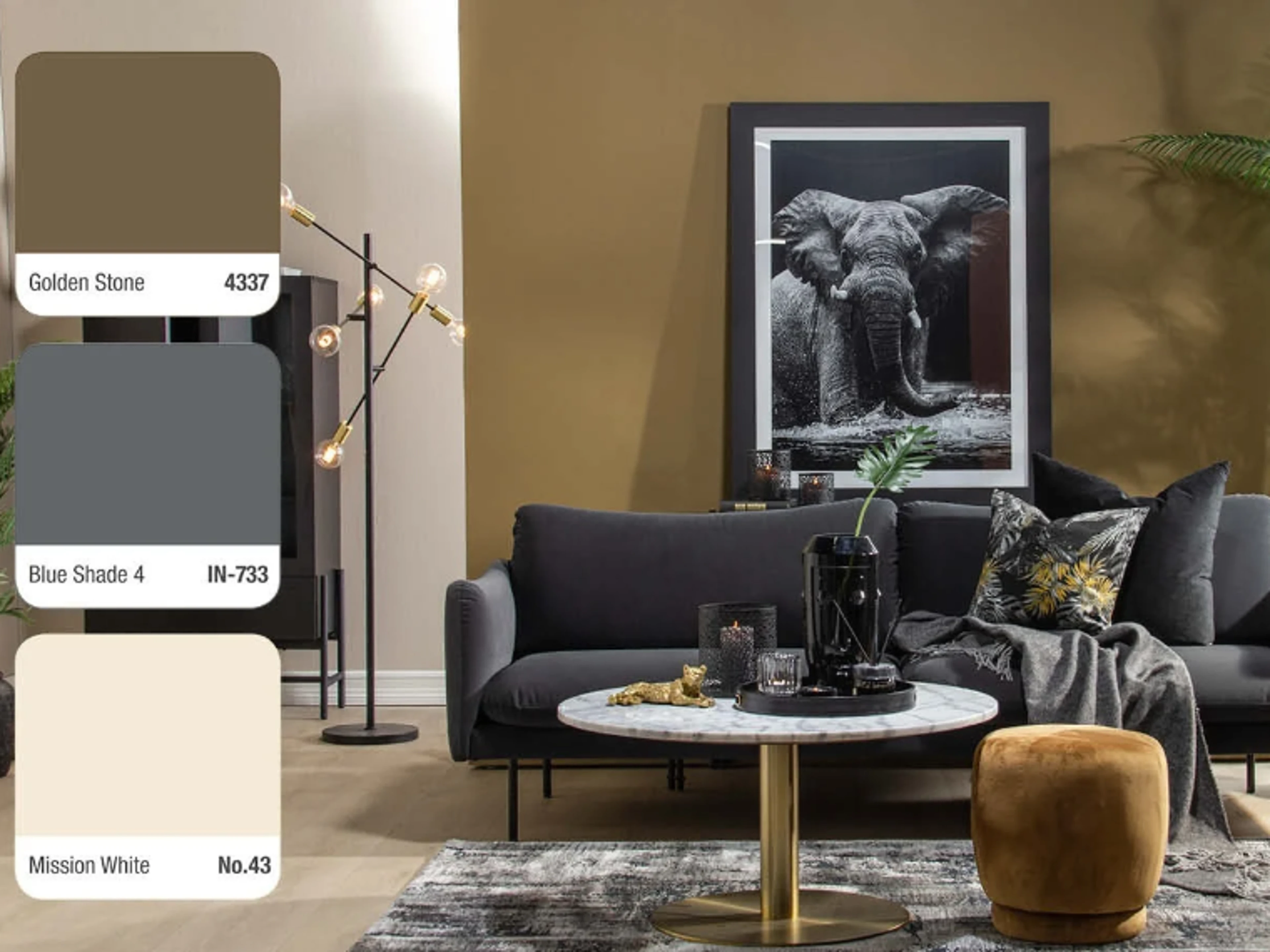 Living room with golden brown and beige walls, a dark grey sofa, a marble and gold coffee table, a large framed elephant photograph and a floor lamp, with three colour swatches on the left: Golden Stone 4337, Blue Shade 4 IN-733 and Mission White No.43.