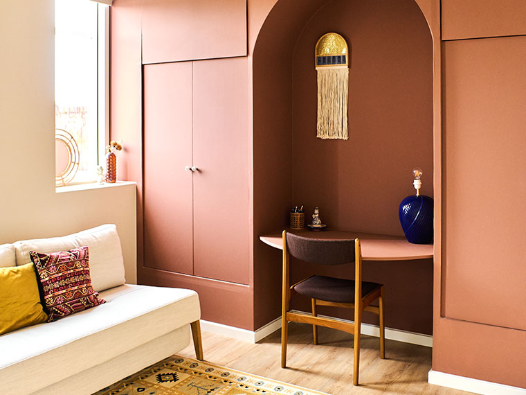 Bright room with terracotta-colored built-in cabinets and a workspace set within an arched alcove.