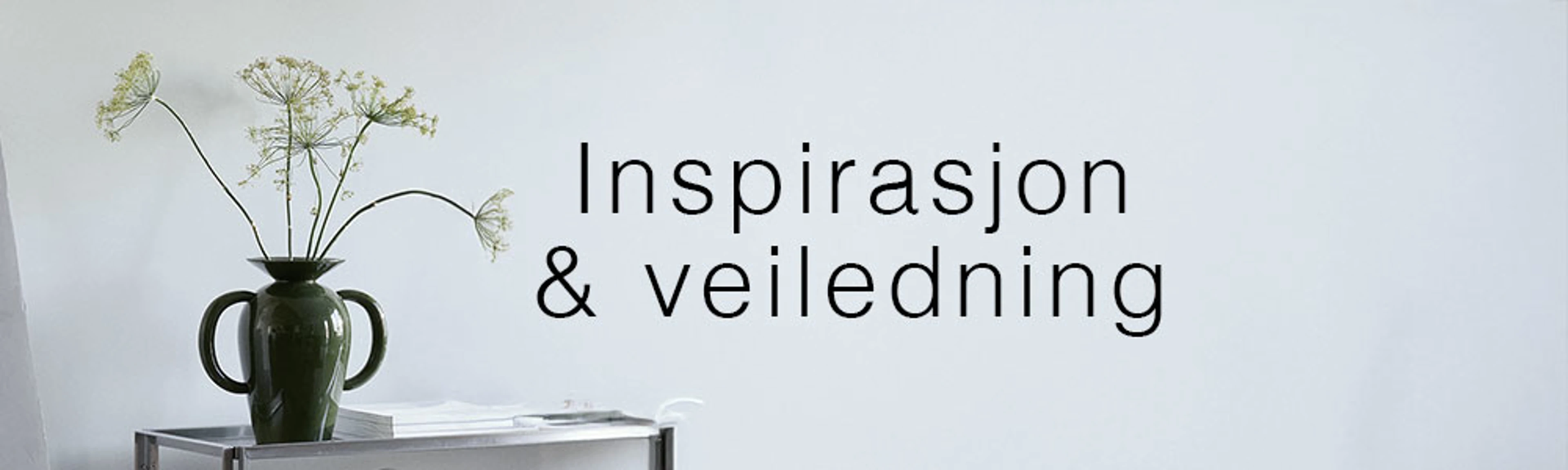 Vase med grønne blomster på et sidebord foran en lys væg med teksten "Inspirasjon & veiledning".