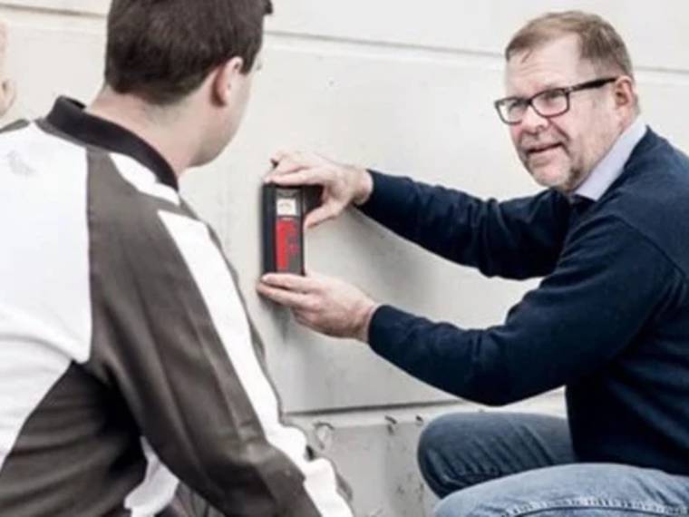 Fluggers teknisk ekspert rådgiver en kunde på malede hvid betonfasade.