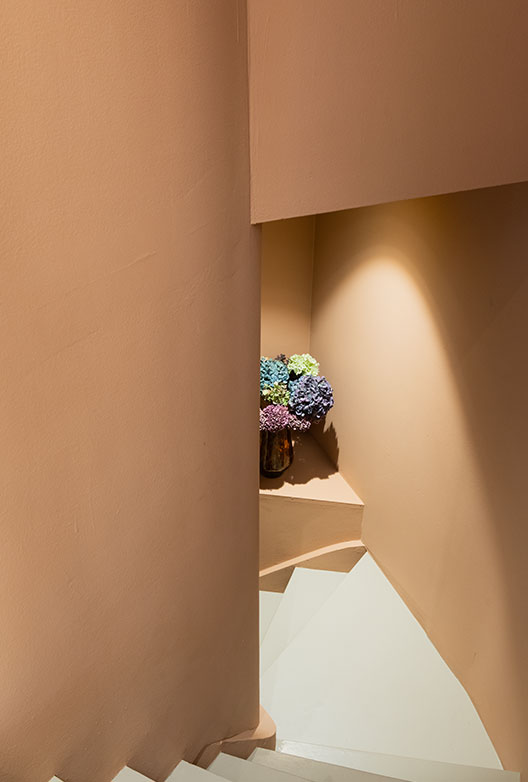 Trappeopgang med indbygget niche og vase med blomster.
