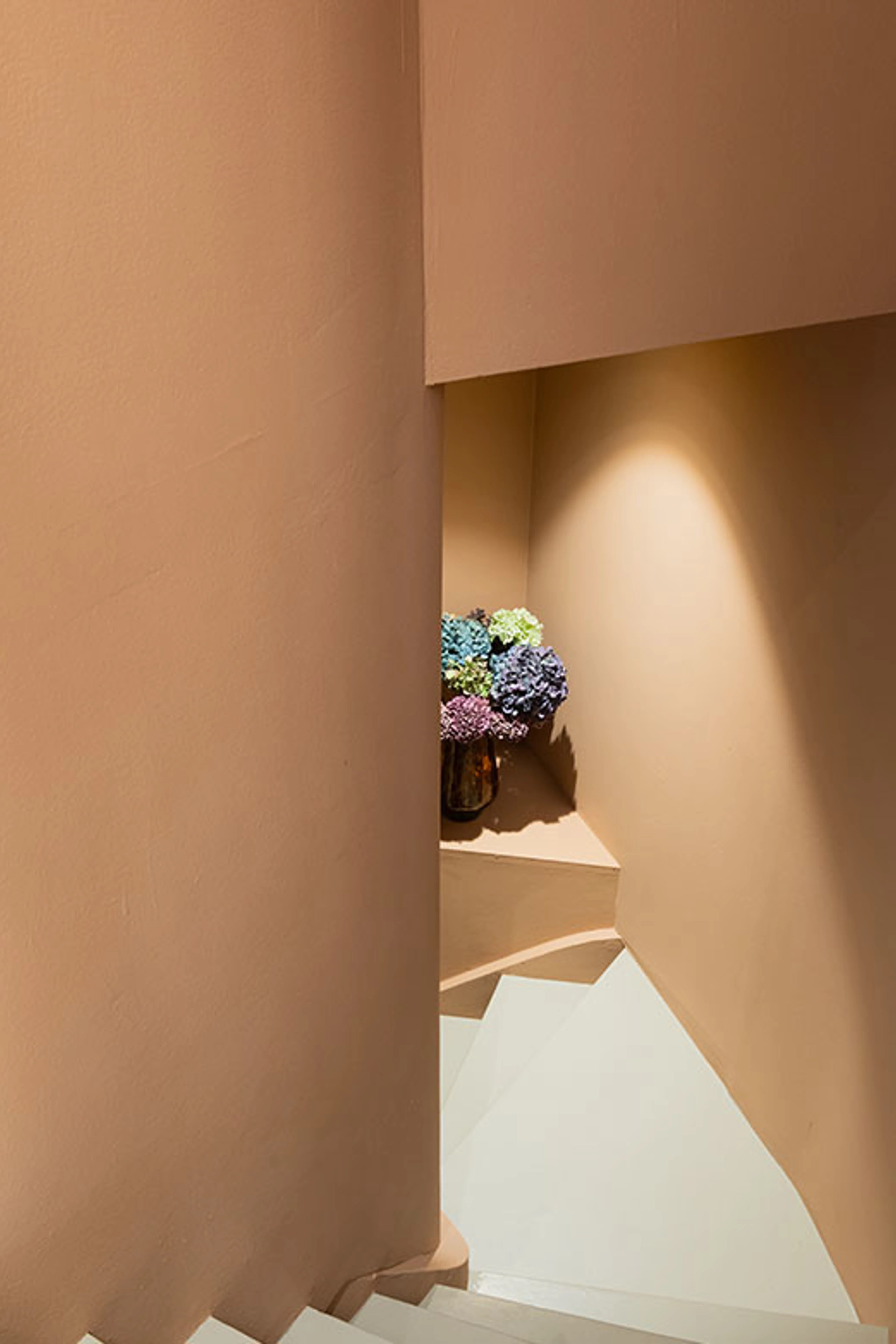 Trappeopgang med indbygget niche og vase med blomster.