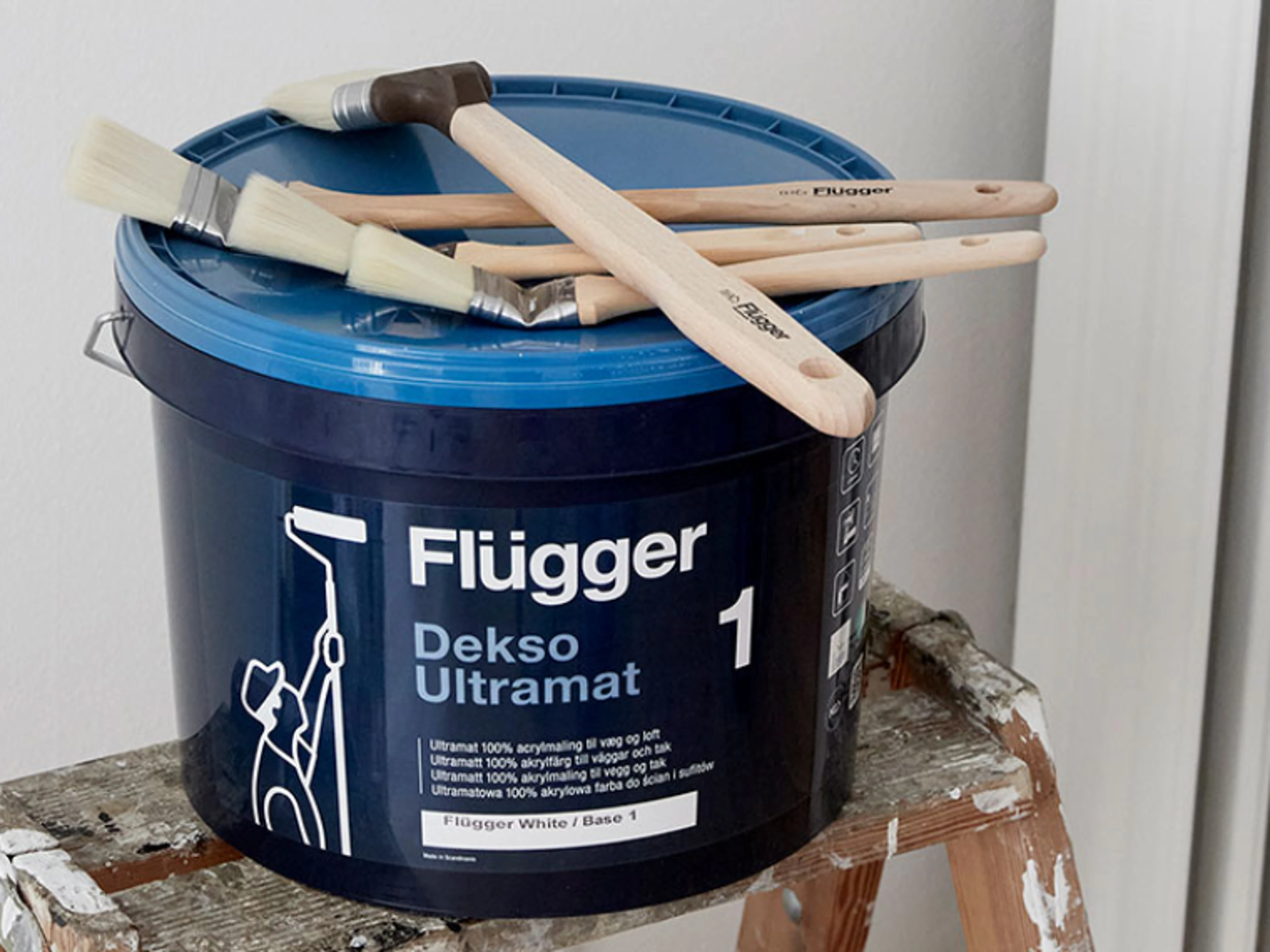 En malingsbøtte fra Flügger med Dekso 1 Ultramatt og pensler oppå.