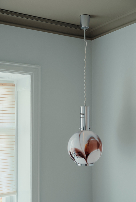Rum med lyse vægge og loftlampe i glas og metal.