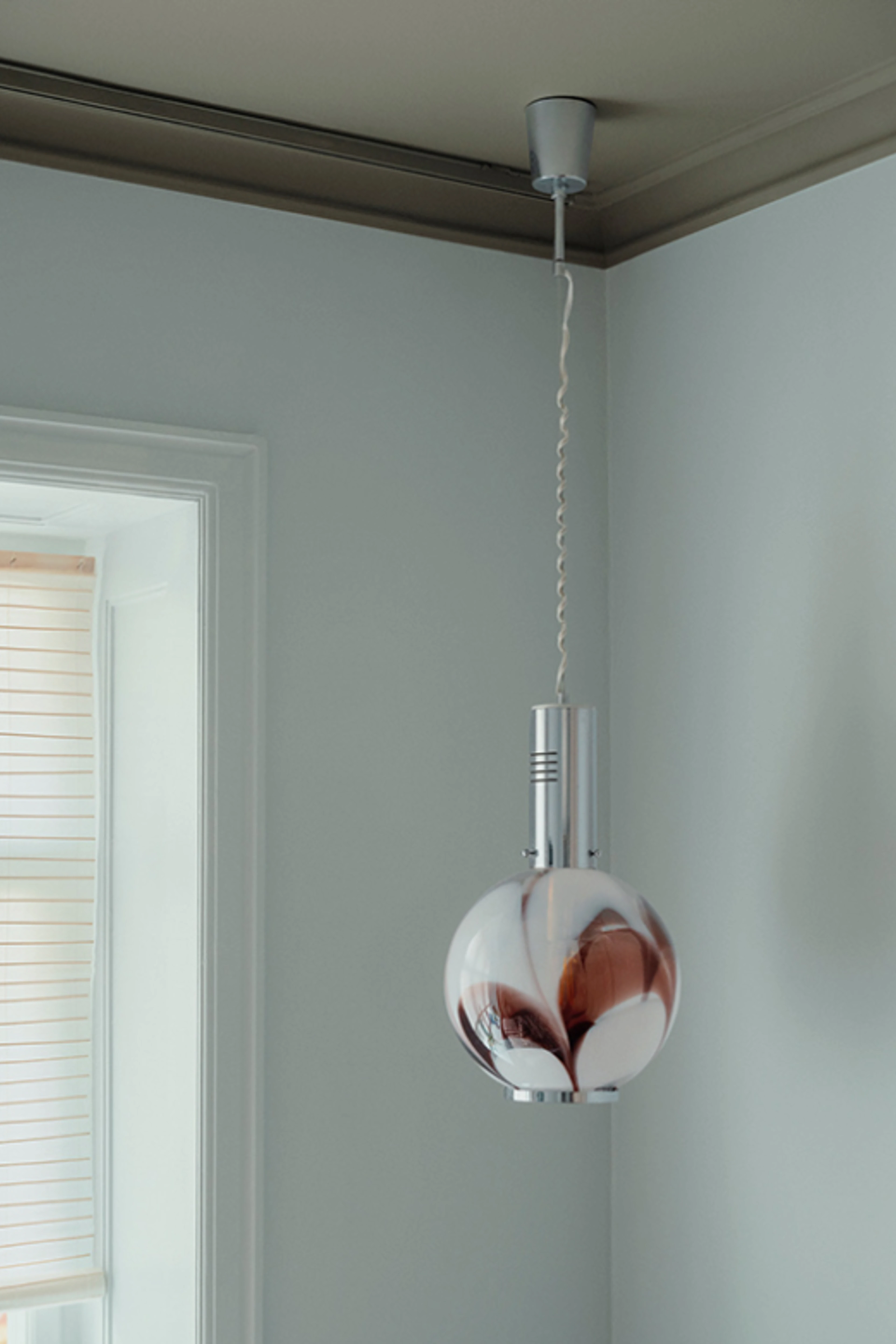 Rum med lyse vægge og loftlampe i glas og metal.