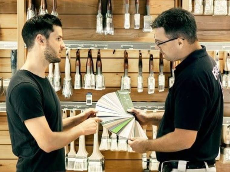 Flugger butiksassistent rådgiver en kunde om farver i butikken.