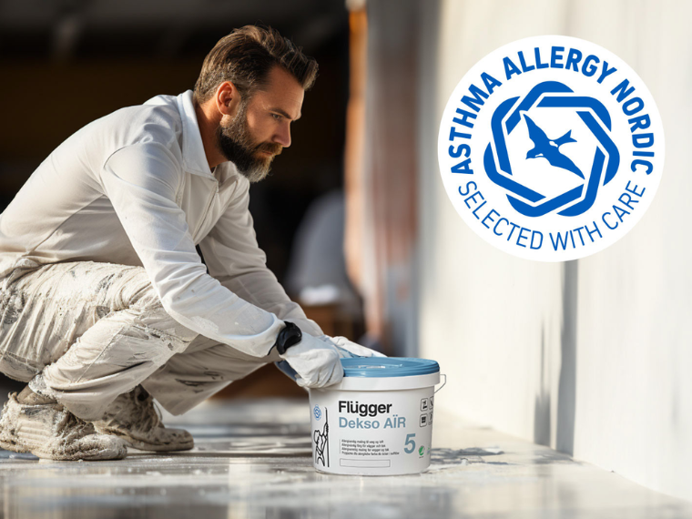 Person by a wall with a bucket of Flügger Dekso Air paint, with the Asthma Allergy Nordic label visible in the image.