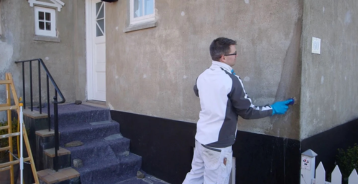 En mand som rengøre en facade på et hus.
