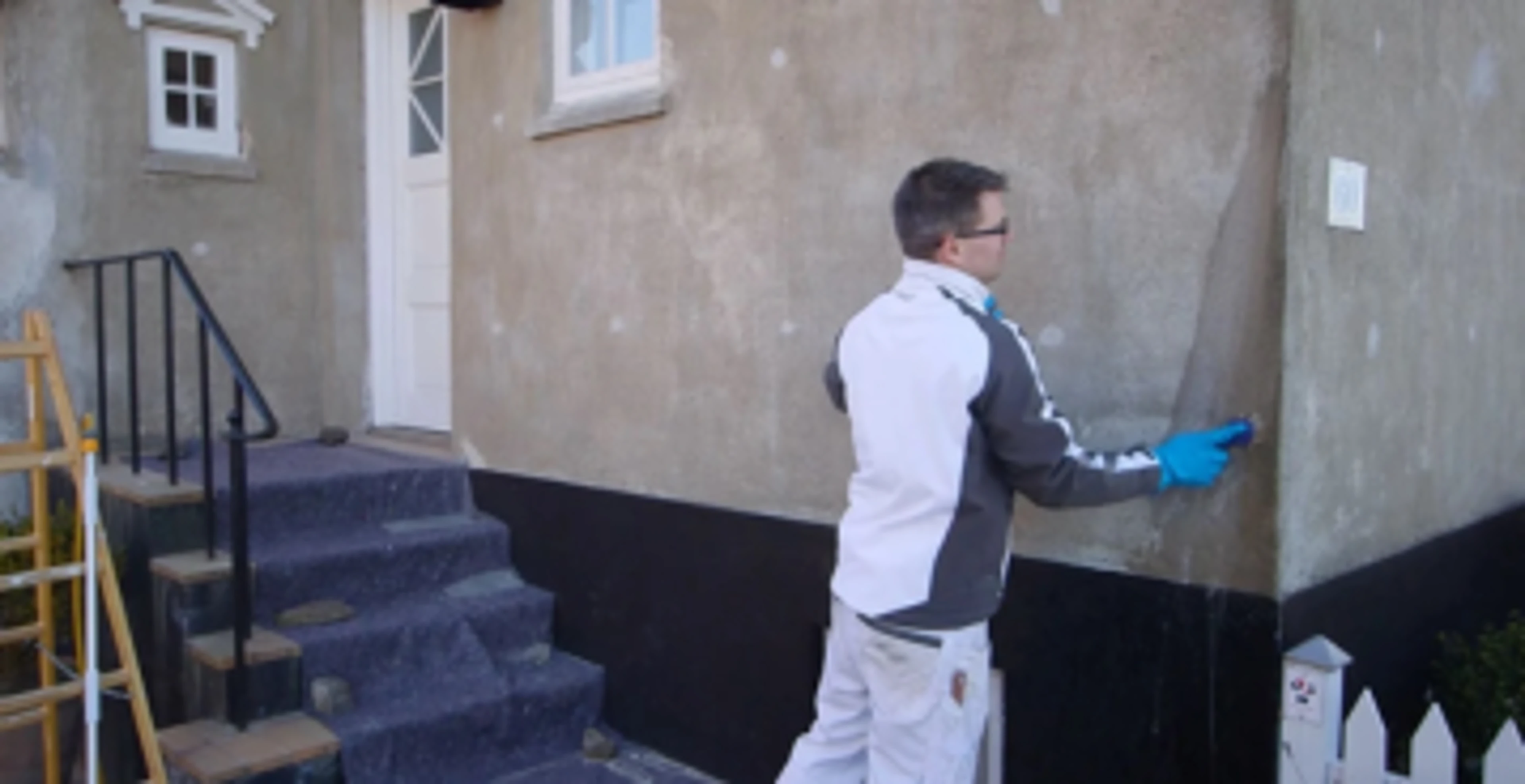 En mand som rengøre en facade på et hus.