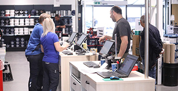 Malerbutik hvor to ansatte ekspedere en kunde.