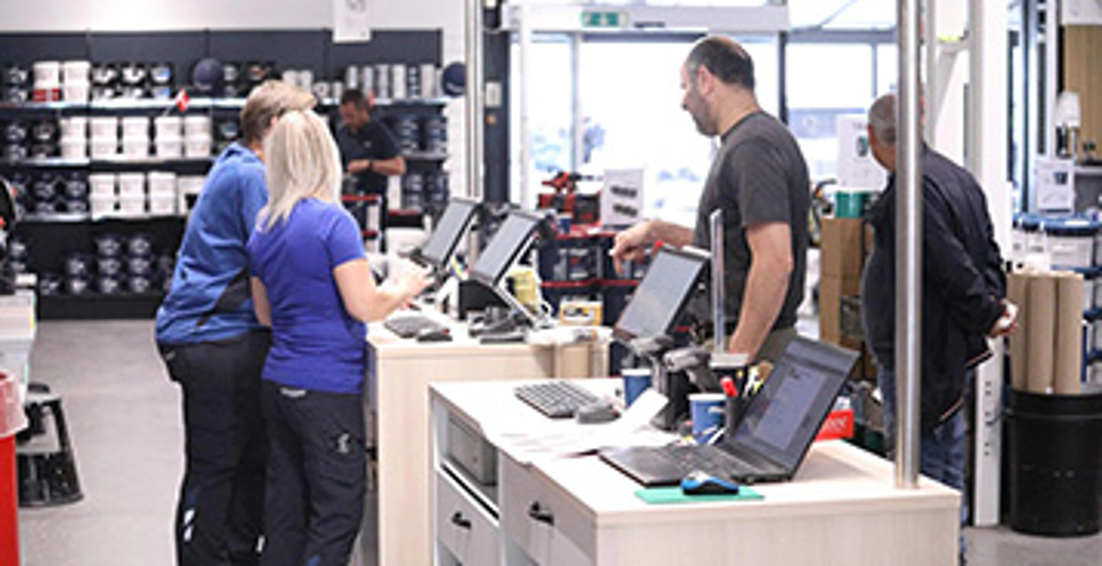 Malerbutik hvor to ansatte ekspedere en kunde.
