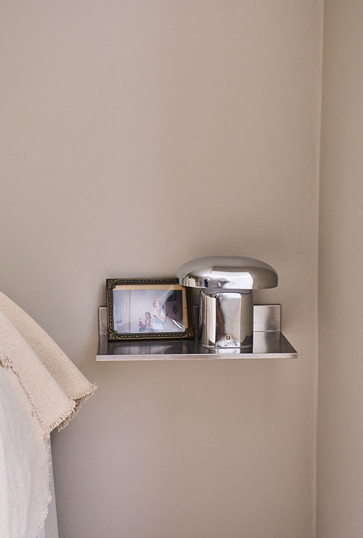 Metalhylde med bordlampe og indrammet fotografi.