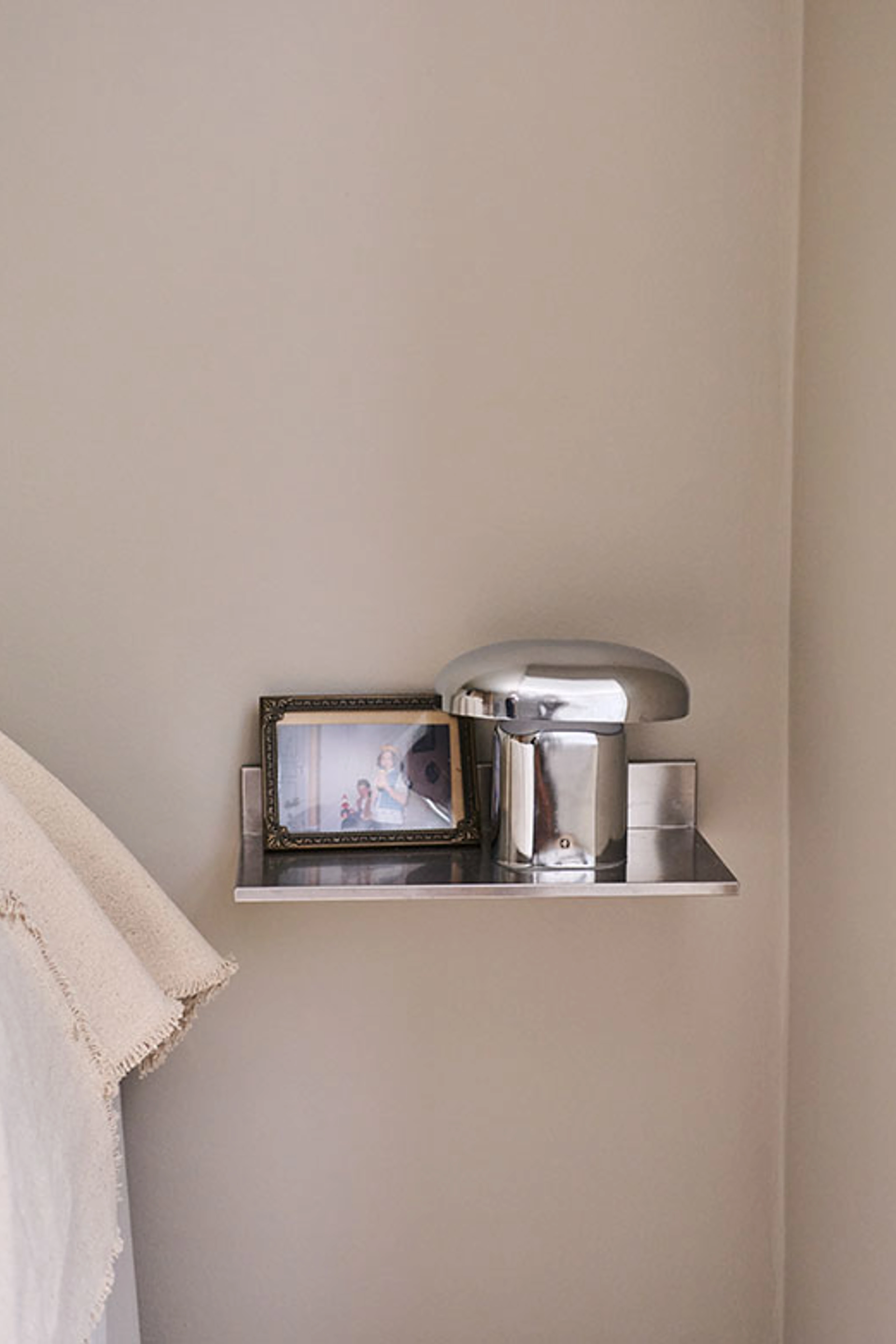 Metalhylde med bordlampe og indrammet fotografi.
