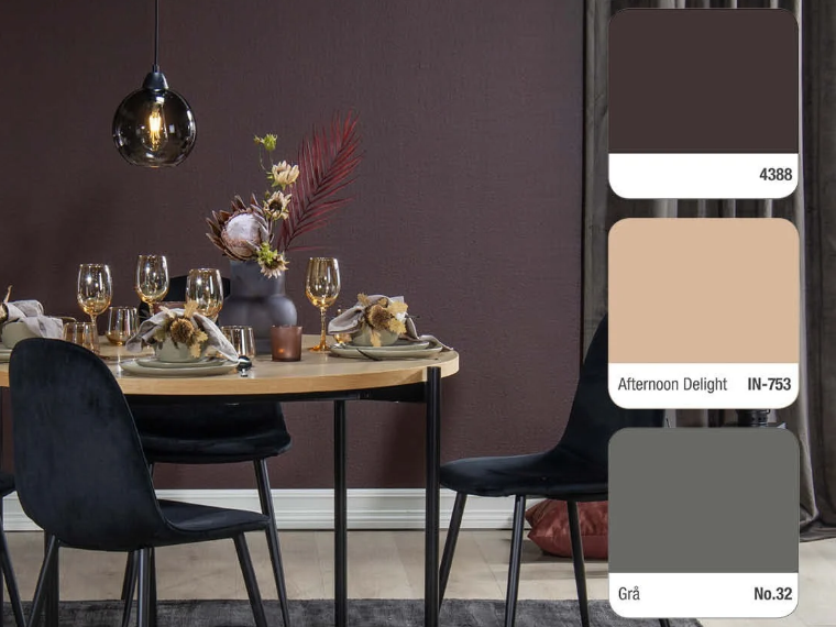 Dining area with dark burgundy walls, a round wooden table set with golden glasses and a floral arrangement, black velvet chairs and a glass pendant lamp, with three colour swatches on the right: 4388, Afternoon Delight IN-753 and Grå No.32.