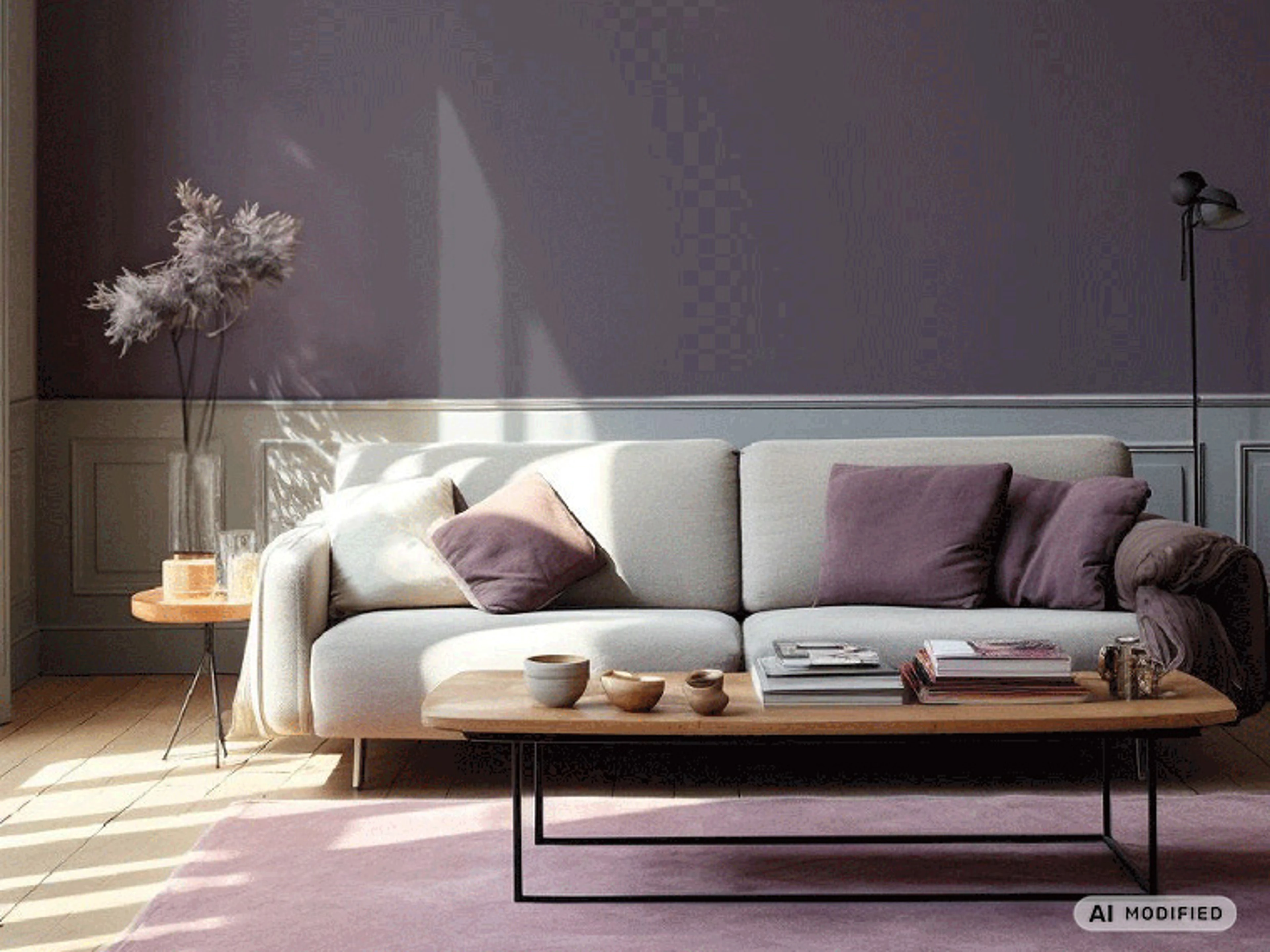 Stue med væg malet i Flügger-farven Kind Purple (FL8057), lys sofa med puder i lilla nuancer, sofabord i træ og sorte metalben samt blødt dagslys, der falder ind gennem vinduet.