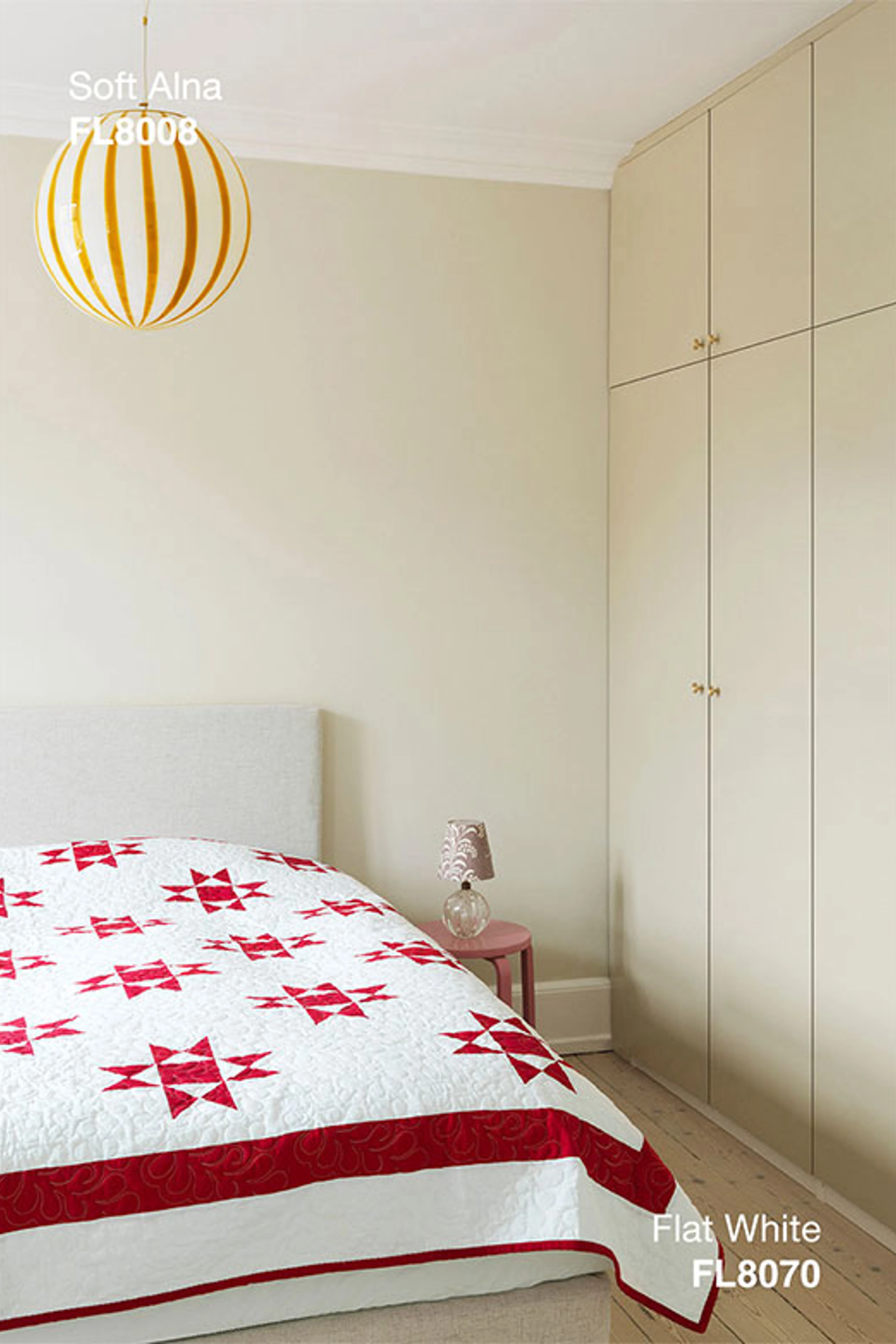 Lyst soveværelse med vægge i Soft Alna og indbyggede skabe i Flat White, indrettet med seng, mønstret sengetæppe og stribet loft lampe.