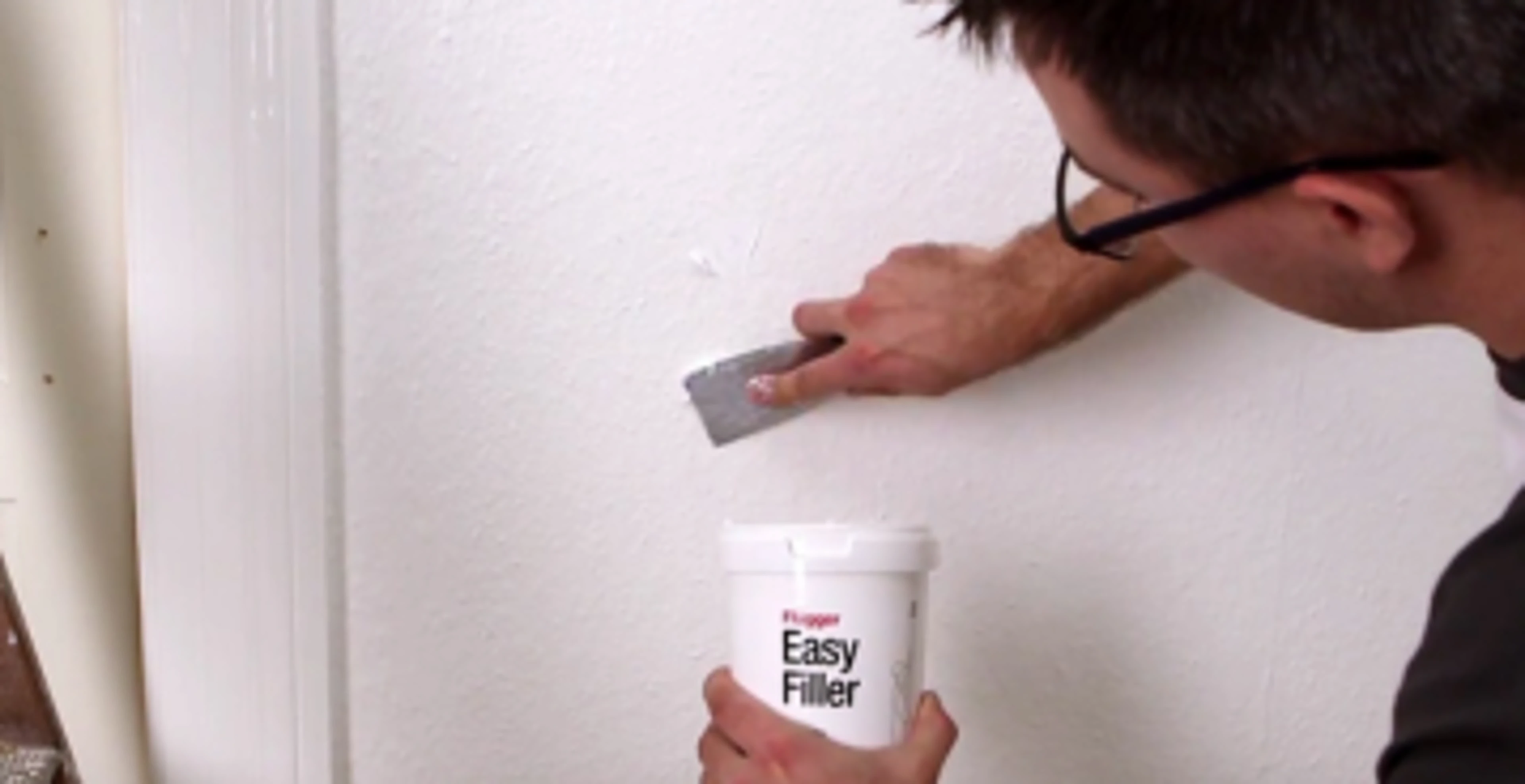 Mand som reparere huller i væggen med easy filler fra Flugger.