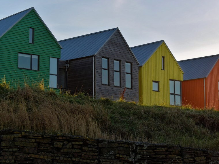 4 træhuse i forskellige farver grøn, sort, gul og orange.