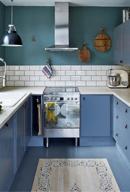 Traditional kitchen with dark teal walls, blue cabinets, white wall tiles and a stainless steel cooker.