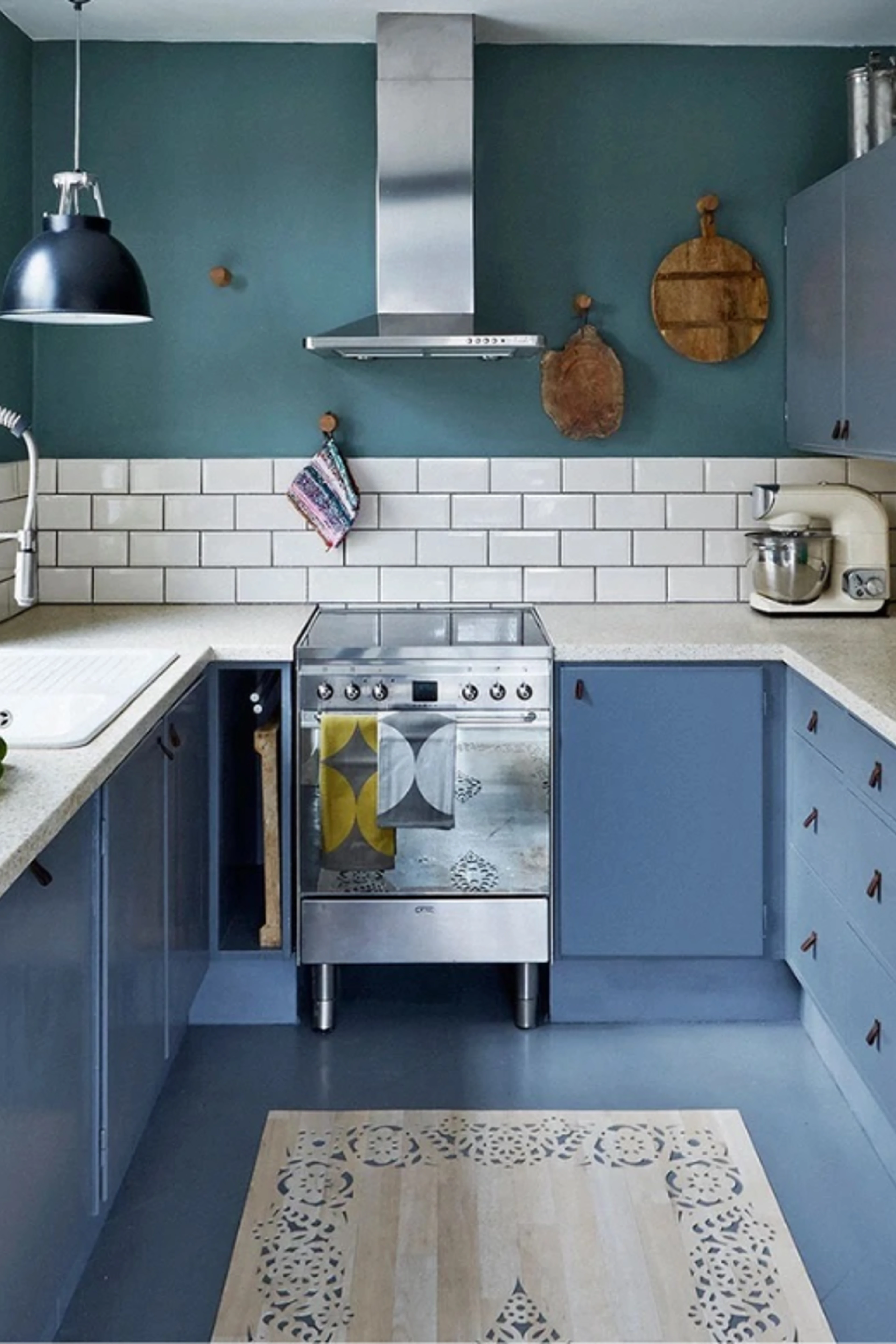 Traditional kitchen with dark teal walls, blue cabinets, white wall tiles and a stainless steel cooker.