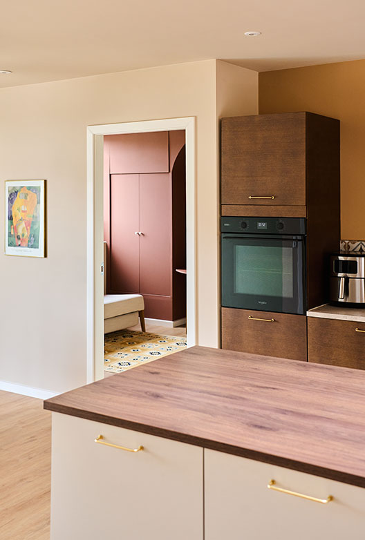 Kitchen with warm beige walls, dark wood cabinets, a white kitchen island, and a view into a terracotta-colored room.