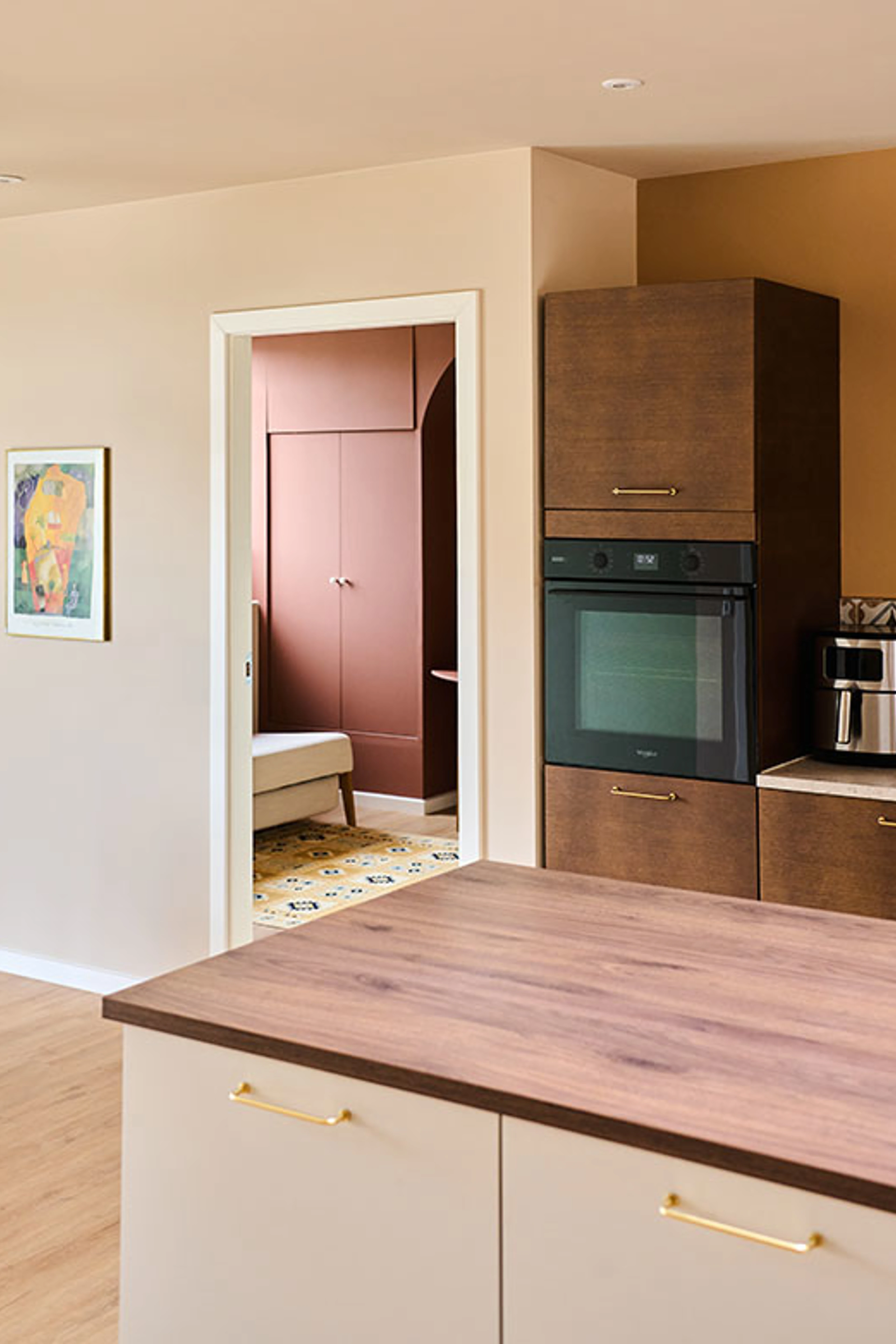 Kitchen with warm beige walls, dark wood cabinets, a white kitchen island, and a view into a terracotta-colored room.
