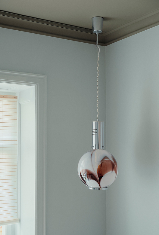 Rum med lyse vægge og loftlampe i glas og metal.
