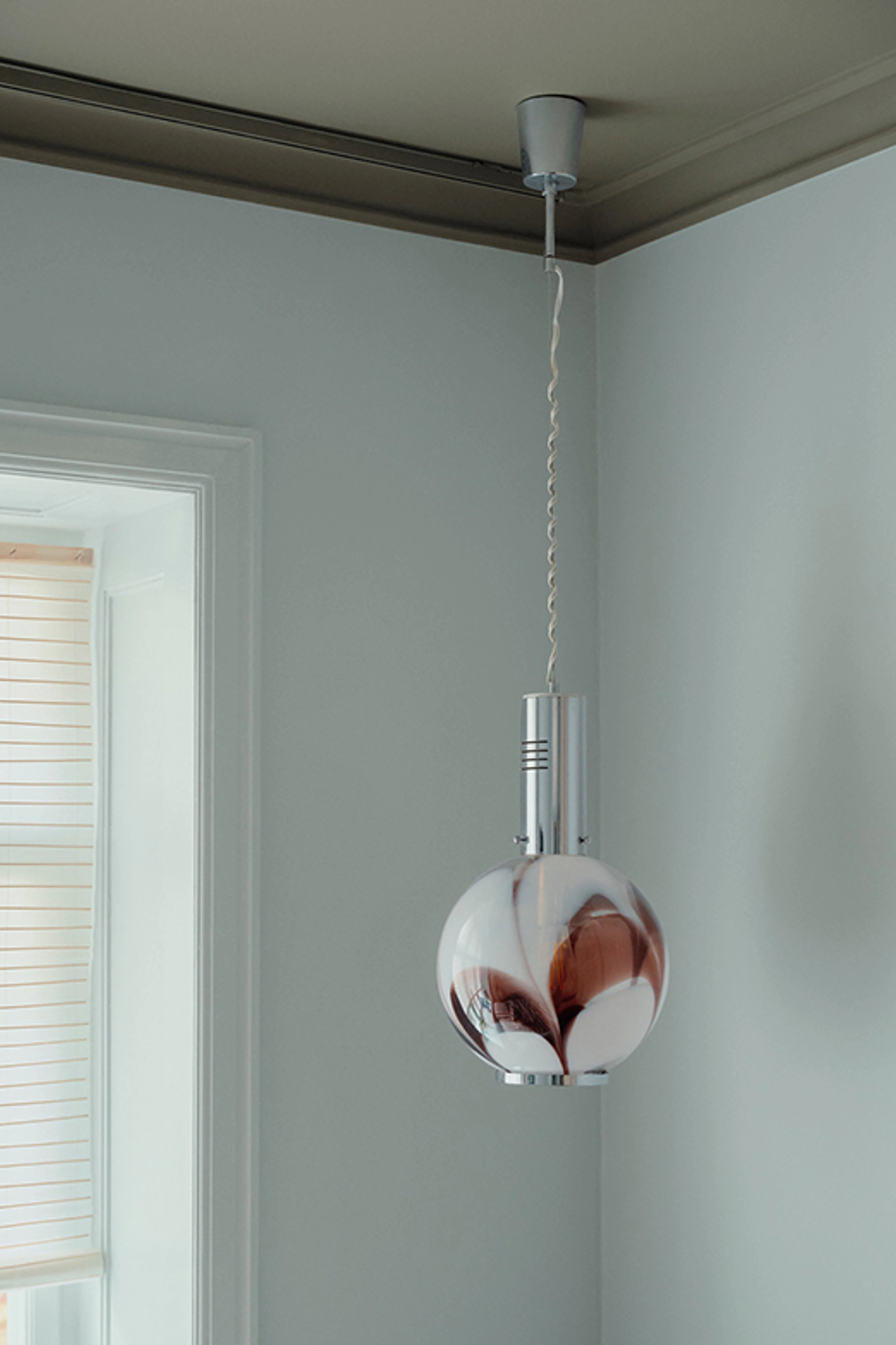 Rum med lyse vægge og loftlampe i glas og metal.
