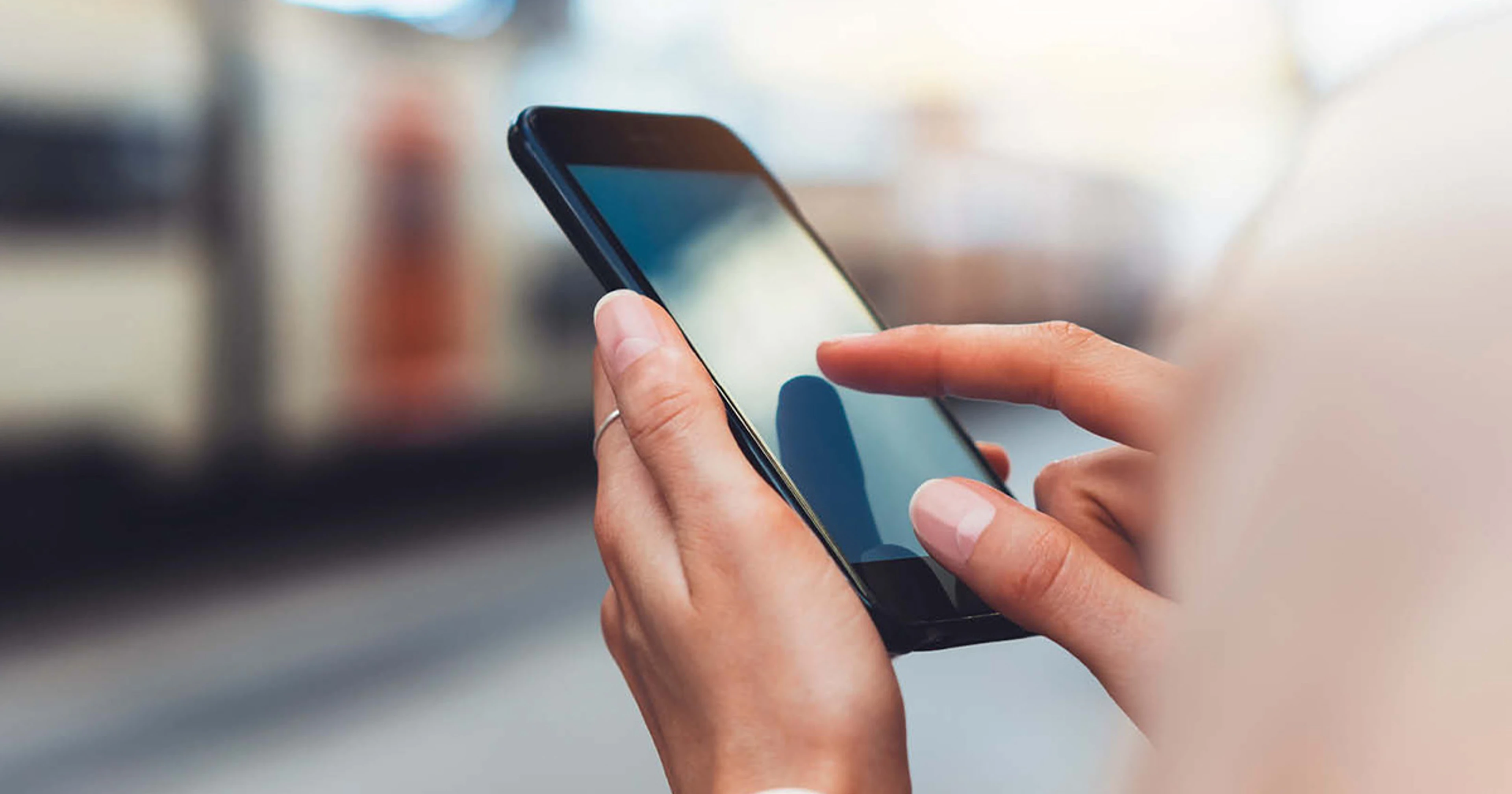 Nærbillede af en hånd, der bruger en smartphone med berøringsskærm.