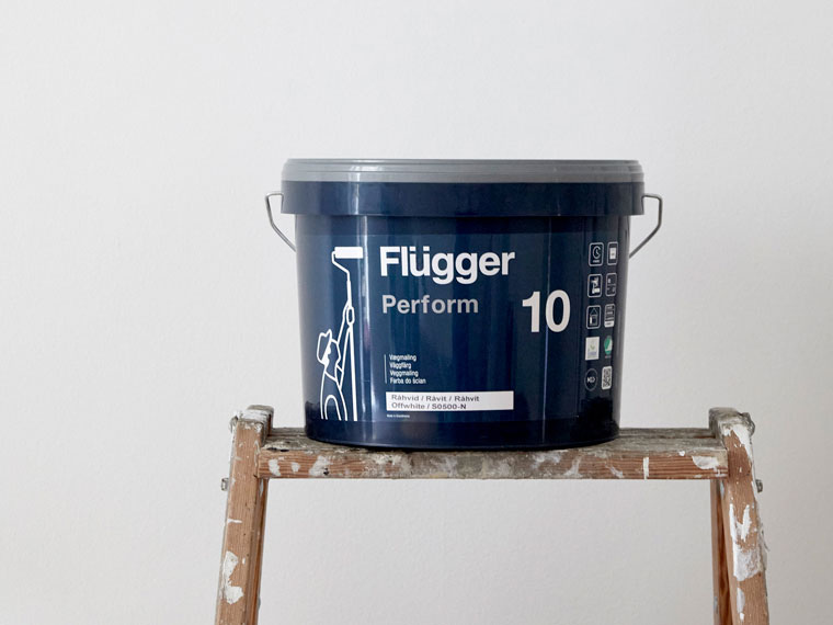 Flügger Perform 10 maling som står oppå en stige mot en hvit bakgrunn.