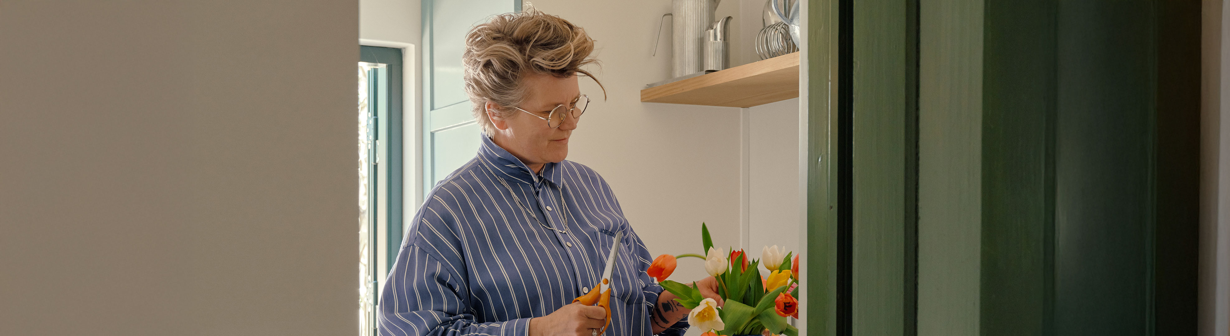 Carla står og arrangerer en buket tulipaner i lyst køkken.