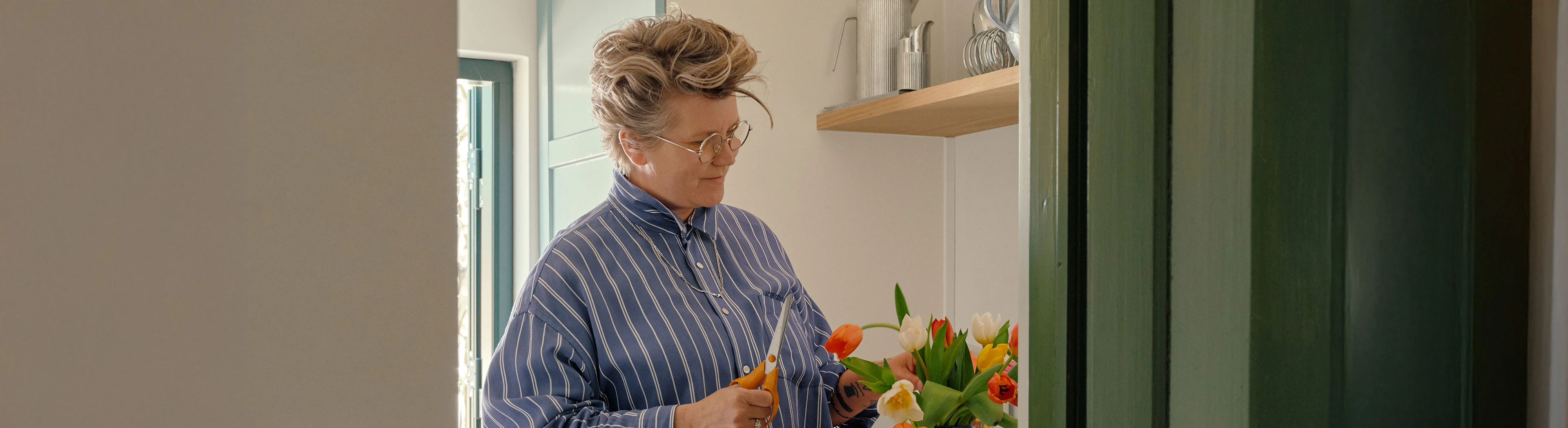 Carla står og arrangerer en buket tulipaner i lyst køkken.