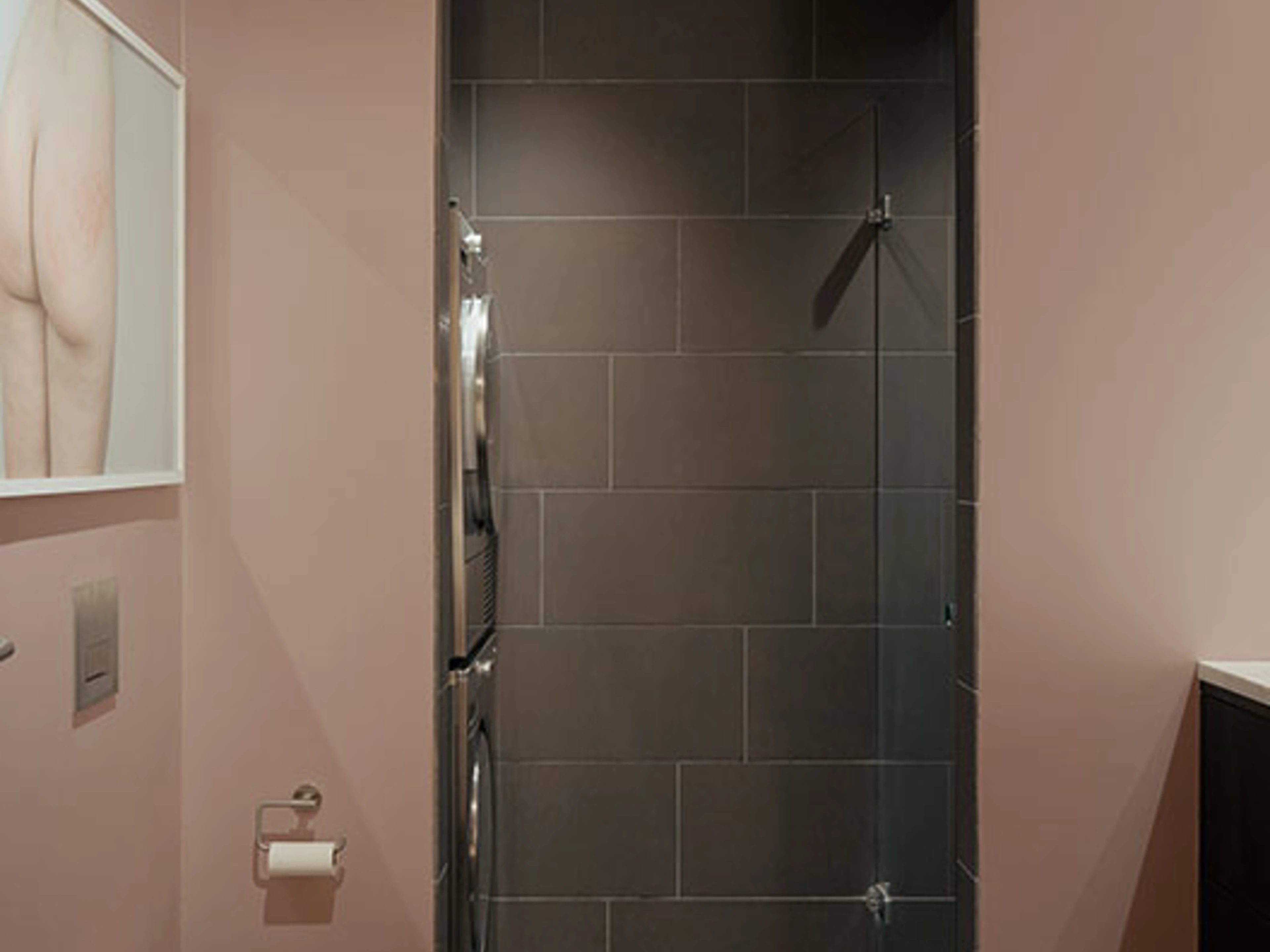 Badeværelse med rosa vægge, bruseniche og væghængt toilet.