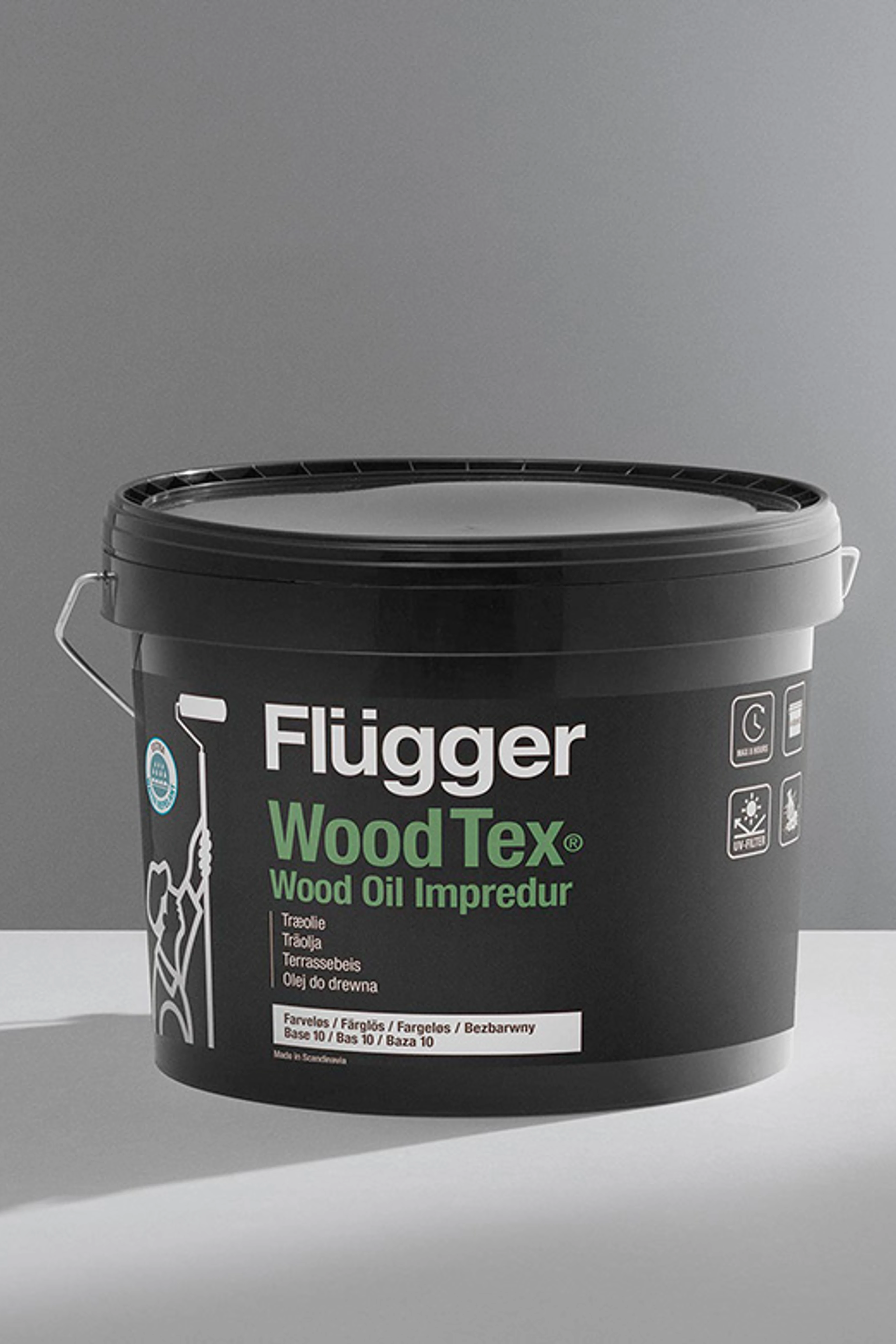 Spand med Flügger Wood Tex Wood Oil Impredur terrasseolie foran en neutral grå baggrund.